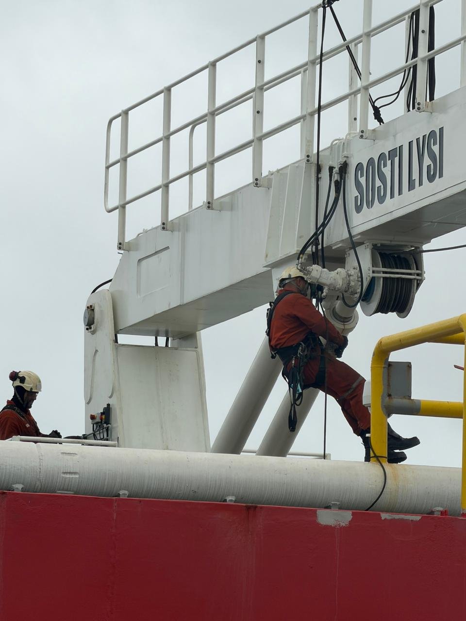 Técnico em acesso por corda trocando mangueira no carretel de um guindaste
